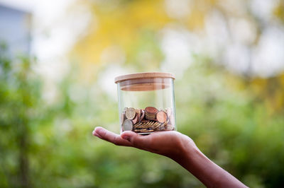 Close-up of hand holding glass jar against blurred background