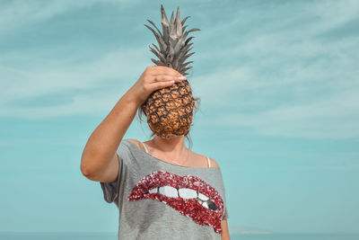 Midsection of woman holding umbrella against sea