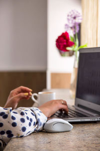 Cropped hands of woman using laptop on table