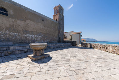 Stone wall by building against sky