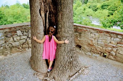 Girl standing by tree trunk