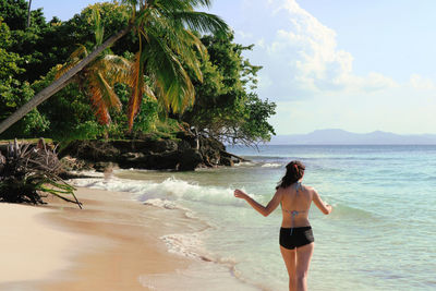 Rear view of woman standing on beach against sky