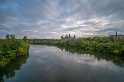 Scenic view of river by buildings against sky