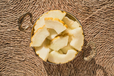 Slices of turkish local yellow melon in a traditional plate on straw deck, top view, 