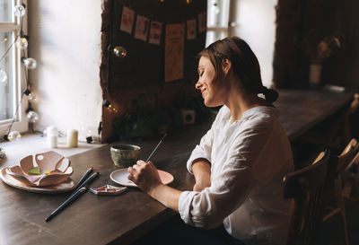 Side view of young woman sitting at table