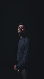 Young man standing against black background