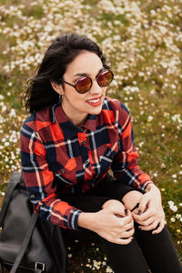 Young woman wearing sunglasses sitting on land