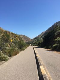 Road amidst mountains against clear blue sky