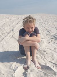 Portrait of boy sitting on sand at beach