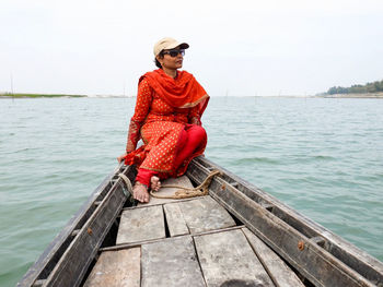 Man sitting on boat in sea against sky