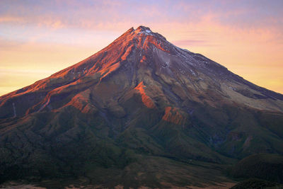 Scenic view of volcanic mountain against sky during sunset