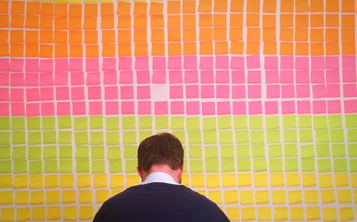 Rear view of businessman against colorful adhesive notes on wall in office