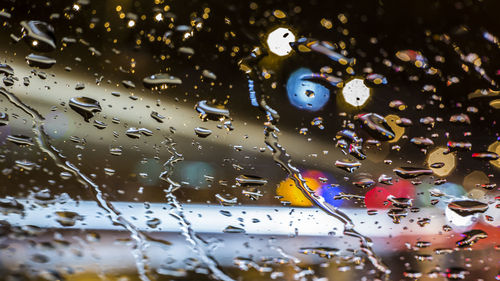 Defocused lights seen through wet car window in rainy season
