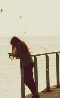 Woman looking at sea shore against sky