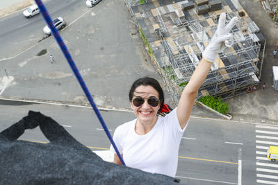 Caucasian woman wearing hero costume descending a tall building in rappel. 