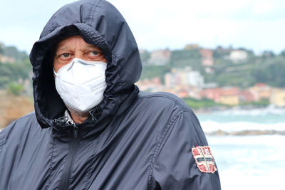 Portrait of senior man wearing mask standing outdoors