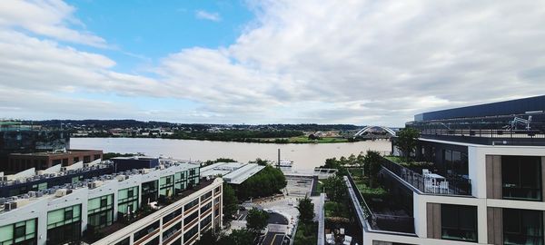 High angle view of buildings by river against sky