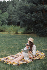 Summer picnic in the park. mother with her little child reading book.