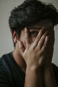 Close-up portrait of young man covering face with hands