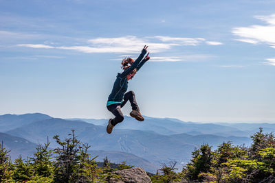 Man jumping on mountain against sky