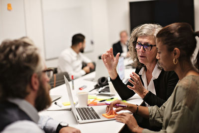 Confident mature professional discussing with colleagues in meeting at conference table