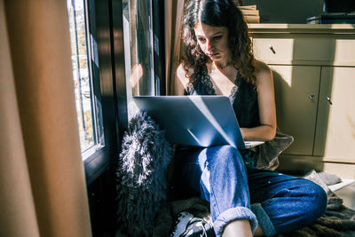 Young woman using mobile phone at home