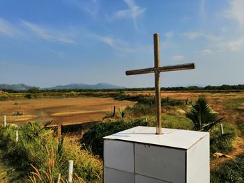 Cross on field against sky