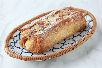 Long square croissant with almond and raspberry and cream cheese filling, on white marble table