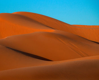 Scenic view of desert against clear blue sky