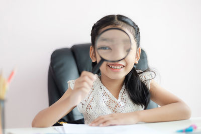 Portrait of a smiling young woman sitting against wall