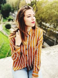 Young woman looking away while sitting outdoors