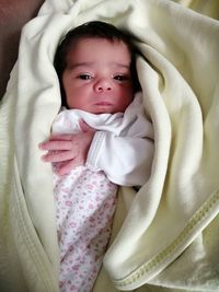 High angle view portrait of cute baby girl lying on bed at home