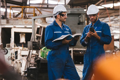 Low angle view of factory workers reading manual in factory