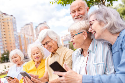 Portrait of smiling friends using smart phone