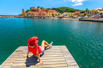 Rear view of man sitting on pier against sky