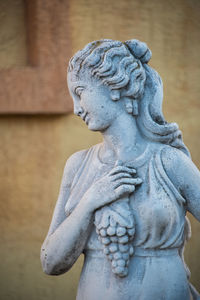 Close-up of female statue against wall