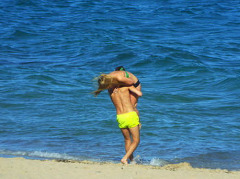 Rear view of man carrying woman at beach