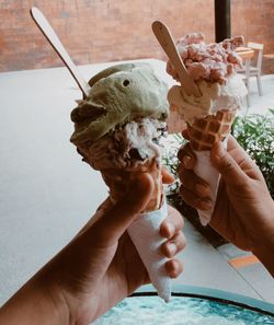 Cropped hands holding ice cream cones at table