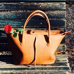 Bag with rose on wooden bench
