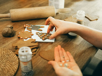 Cropped hand decorating gingerbread cookies during christmas