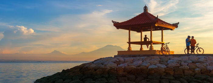 People with bicycles at gazebo by sea