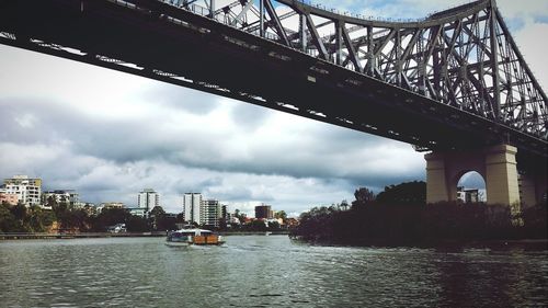 Bridge over river against cloudy sky