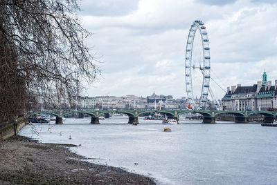 Bridge over river by city against sky