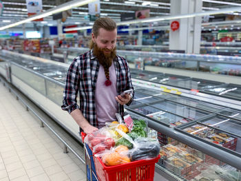 Side view of young woman standing in supermarket