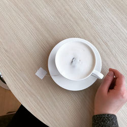 High angle view of hand holding coffee cup on table