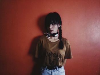 Young woman standing against red wall