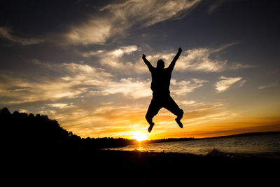 Silhouette man jumping at sunset