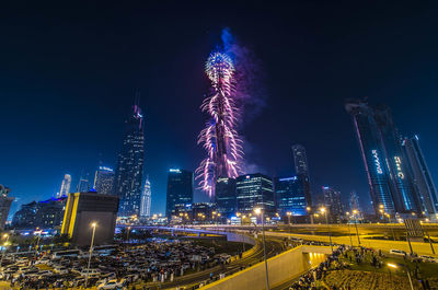 Firework display in city against sky at night