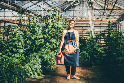 Rear view of young woman standing against plants