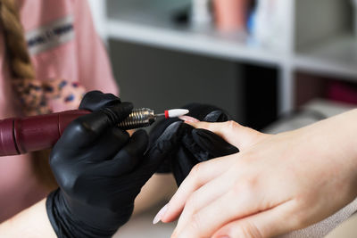 A manicurist removes gel polish from nails using a milling cutter. hardware manicure close-up. 